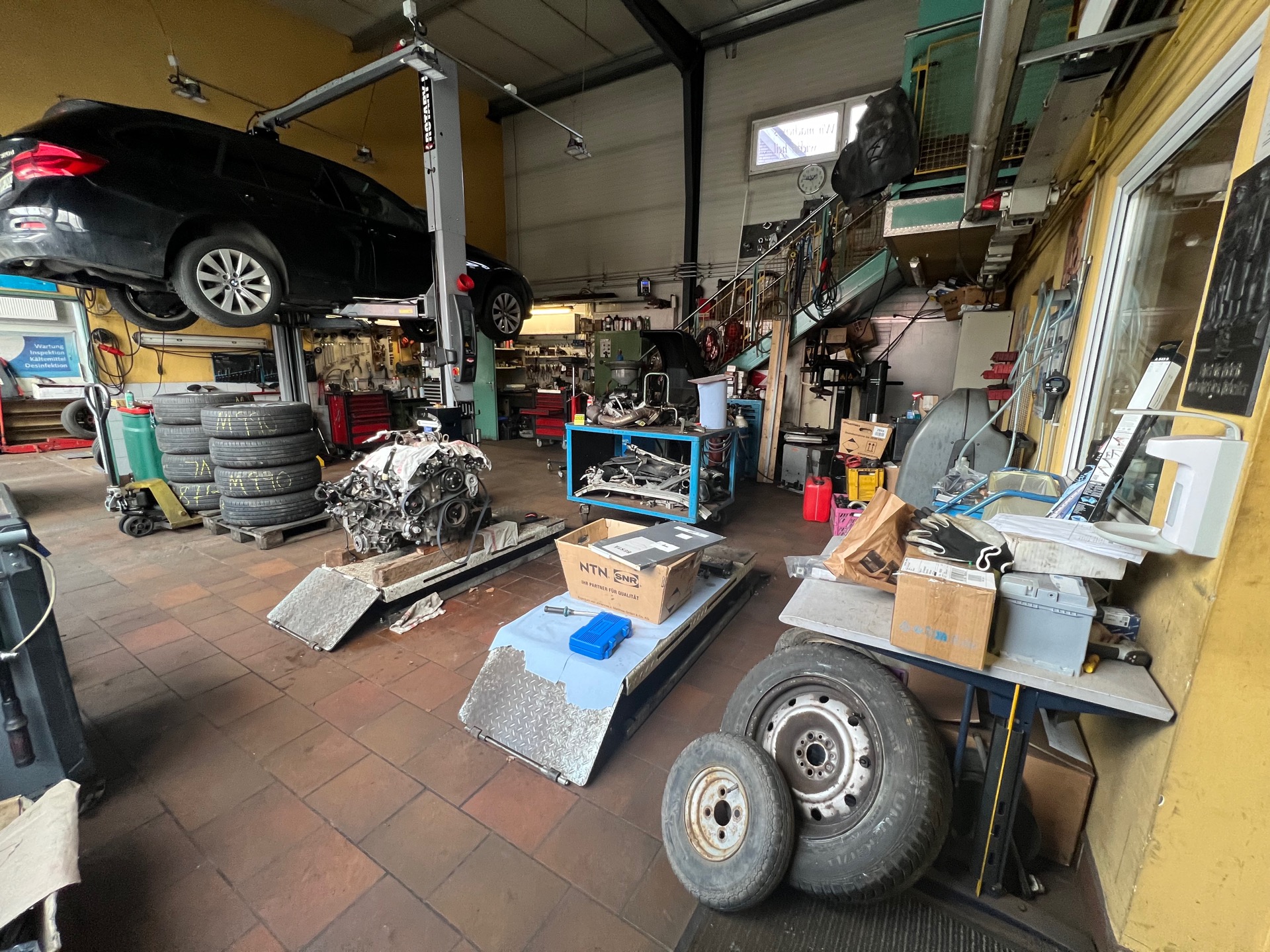 Blick in die Werkstatthalle mit Auto auf der Hebebühne